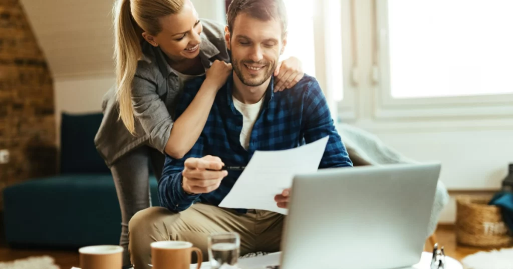 Casal revisando orçamento financeiro em laptop, simbolizando planejamento financeiro para casais em 2025.
