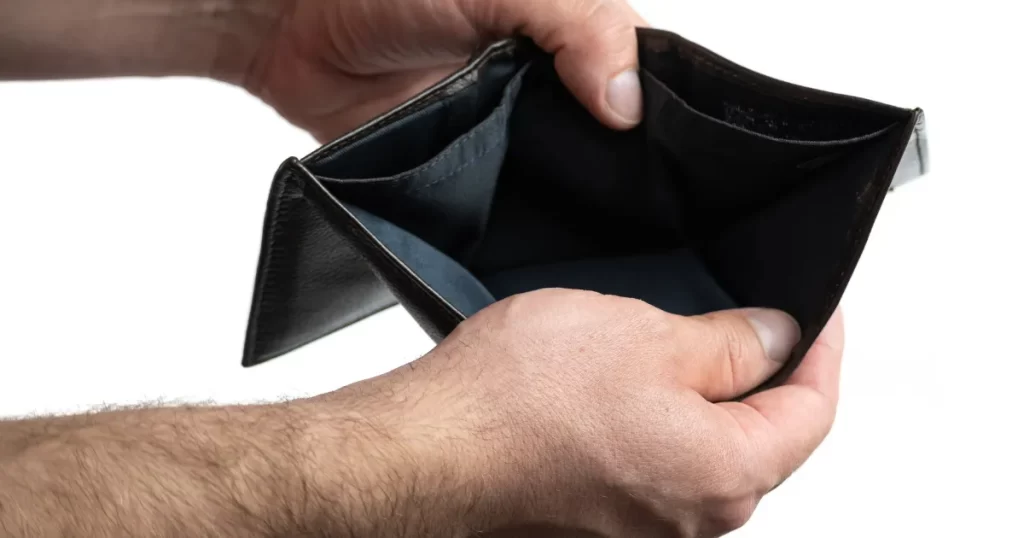 Homem abrindo uma carteira vazia, simbolizando a falta de controle financeiro