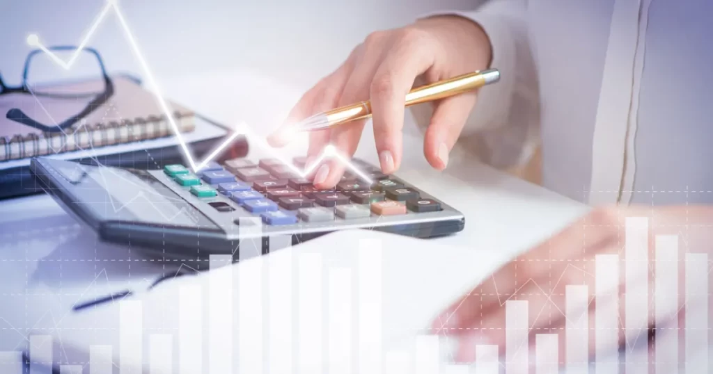 Mão de analista financeiro usando calculadora para análise de balanços, com gráfico de crescimento e desempenho de empresa.