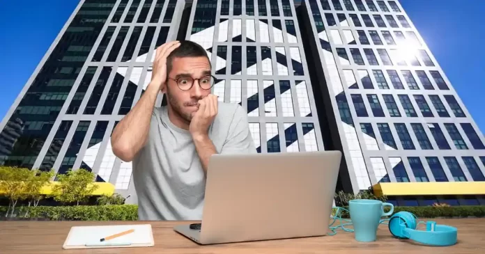 Homem preocupado olhando o preço das ações de BBAS3 em seu notebook, com o prédio do Banco do Brasil ao fundo.