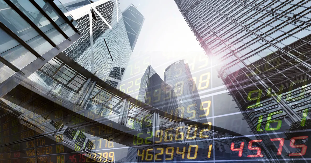 Foto de arranha-céus de um centro financeiro com uma sobreposição de números de mercado de ações, que representa a volatilidade e as oportunidades do setor.
