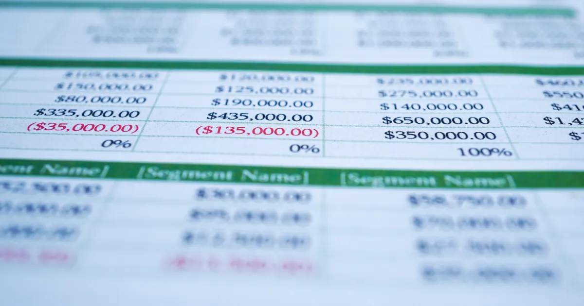 Close-up de uma planilha financeira com dados de receita e despesas, incluindo valores negativos em vermelho, simbolizando a análise de custos para a precificação de um negócio.