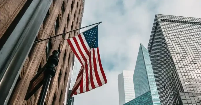 Bandeira dos EUA em centro financeiro, simbolizando a economia americana, o payroll e as expectativas de corte de juros pelo FED.