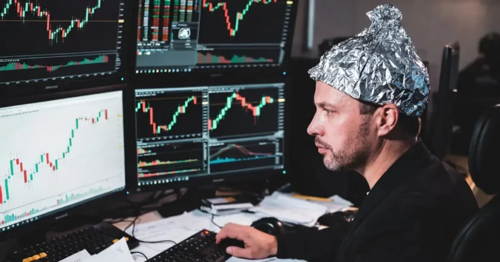 Trader com chapéu de alumínio analisando múltiplos monitores com gráficos de candlestick e padrões de Fibonacci, representando análise técnica versus narrativa de mercado