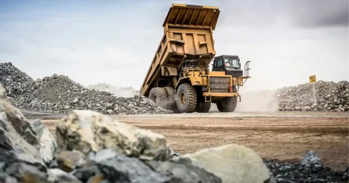 Caminhão basculante carregado de minério de ferro em operação de mineração, representando a produção de commodities da Vale
